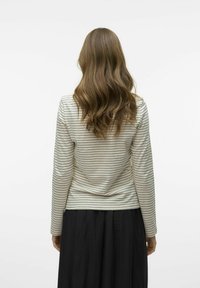 Lange mouwen top met een romige basis en smalle zwarte strepen, gemaakt van een zachte, gestructureerde stof, gecombineerd met een vloeiende zwarte rok.