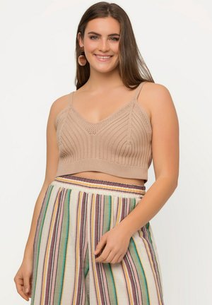 Gebreide crop top in een lichtbeige kleur met een v-hals en ribbeltextuur, gecombineerd met gestreepte wijde broek in meerdere kleuren.