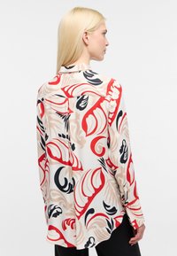 Blusa a maniche lunghe in tessuto leggero, caratterizzata da una stampa astratta colorata nei toni del rosso, nero e beige, con colletto classico e polsini con bottoni.