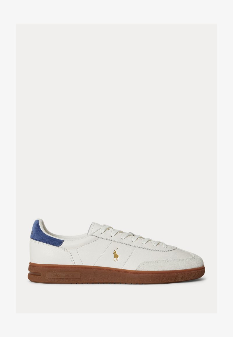 Baskets basses blanches avec semelle marron, languette de talon en cuir suédé bleu, logo Polo Ralph Lauren doré sur le côté et lacets blancs.
