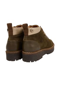 Bottes de cheville en suède vert et cuir avec une semelle en caoutchouc marron, des détails cousus et un design bicolore avec une languette.