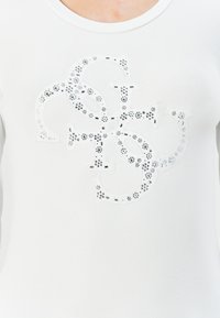 Weißes T-Shirt mit einem strukturierten, gestickten Logodesign, verziert mit klaren und schwarzen Strasssteinen für zusätzliches Detail.