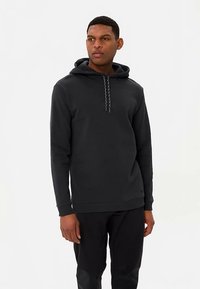 Schwarzer Hoodie aus weichem Stoff, mit Kordelzug an der Kapuze, gerippten Bündchen und lockerem Schnitt. Einfaches, minimalistisches Design ohne Muster.