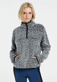 Fleece-Pullover aus schwarzem und weißem strukturiertem Stoff mit einem Reißverschlusskragen, seitlichen Taschen und Kontrastbesatz entlang der Bündchen und des Saums.