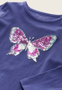 Lila T-Shirt mit einem Schmetterlingsdesign aus mehrfarbigen Pailletten, akzentuiert mit Silber, Pink und Weiß. Runde Halslinie und weicher Stoff.