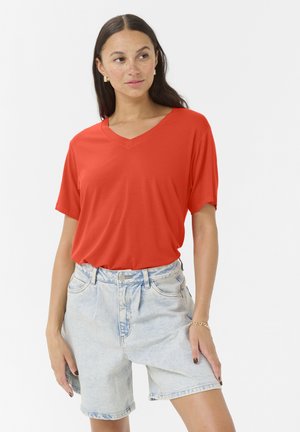 T-shirt rouge à col en V à manches courtes en tissu doux, associé à un short en denim taille haute bleu clair, offrant une coupe décontractée.