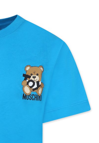 T-shirt in cotone blu con una grafica di un orsetto dei cartoni animati che tiene un grande testo "Toy" in bianco e nero, con "Moschino" stampato sotto il design.