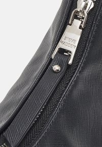 Black textured fabric bag featuring a silver metal zipper with a branded pull tab and a sleek, streamlined design.