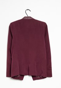 Bordeauxblazer met een gladde textuur, voorzien van een leren kraag, twee zijzakken en een gespleten achterkant, hangend aan een zwarte haak.