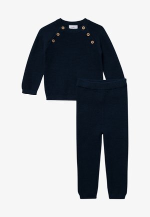 Pull en maille bleu marine avec des accents de boutons en bois aux épaules et un pantalon ajusté assorti. Texture douce, encolure arrondie, poignets et taille côtelés.