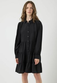 Abito nero con bottoni, maniche lunghe a sbuffo, orlo a strati con ruches, realizzato in un tessuto leggero, con colletto e una leggera lucentezza.