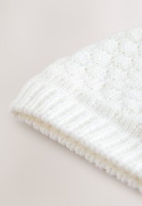 Berretto bianco lavorato a maglia con motivo strutturato e bordo a coste. Realizzato in materiale morbido e caldo per comfort e calore.