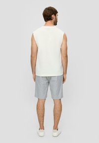 White sleeveless shirt paired with gray shorts. The shirt has a relaxed fit, and the shorts feature a light, textured fabric. White sneakers included.