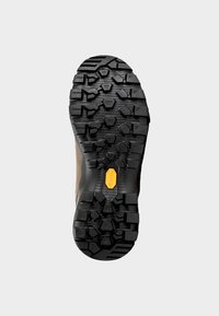 Suola in gomma nera con un intenso motivo a intaglio, caratterizzata da forme esagonali e angolari distinte. Include un elemento logo in gomma gialla.