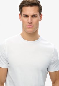 Hvid bomulds T-shirt med rund halsudskæring og korte ærmer. Glat tekstur, minimalistisk design, tætsiddende form, ingen synlige mønstre eller accenter.