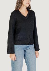 Maglione nero lavorato a maglia con scollatura a V, polsini e orlo a coste. Presenta una finitura texture e una silhouette aderente con leggero svaso alle maniche.