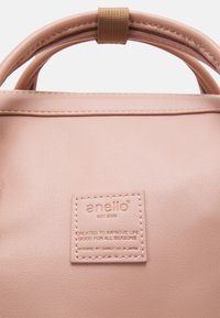 Różowa syntetyczna torebka z podwójnymi uchwytami, zamknięciem na zamek i teksturowanym wykończeniem. Posiada metkę markową z wytłoczonym napisem z przodu.