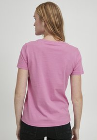 Lyserød bomulds t-shirt med korte ærmer og en rund halsudskæring, der har en glat tekstur og et enkelt, udekoreret design.