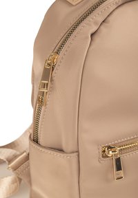 Zaino in nylon beige con cerniere dorate, caratterizzato da due scomparti con zip e spallacci regolabili.