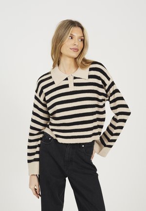 Striped sweater in beige and black, featuring a collared neckline and button details. Soft texture with loose fit, paired with black jeans.