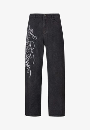 Mustat farkut, joissa on löysä istuvuus, ja vasemmalla puolella on näkyvää valkoista koristeompeleet. Perinteinen viiden taskun muotoilu.