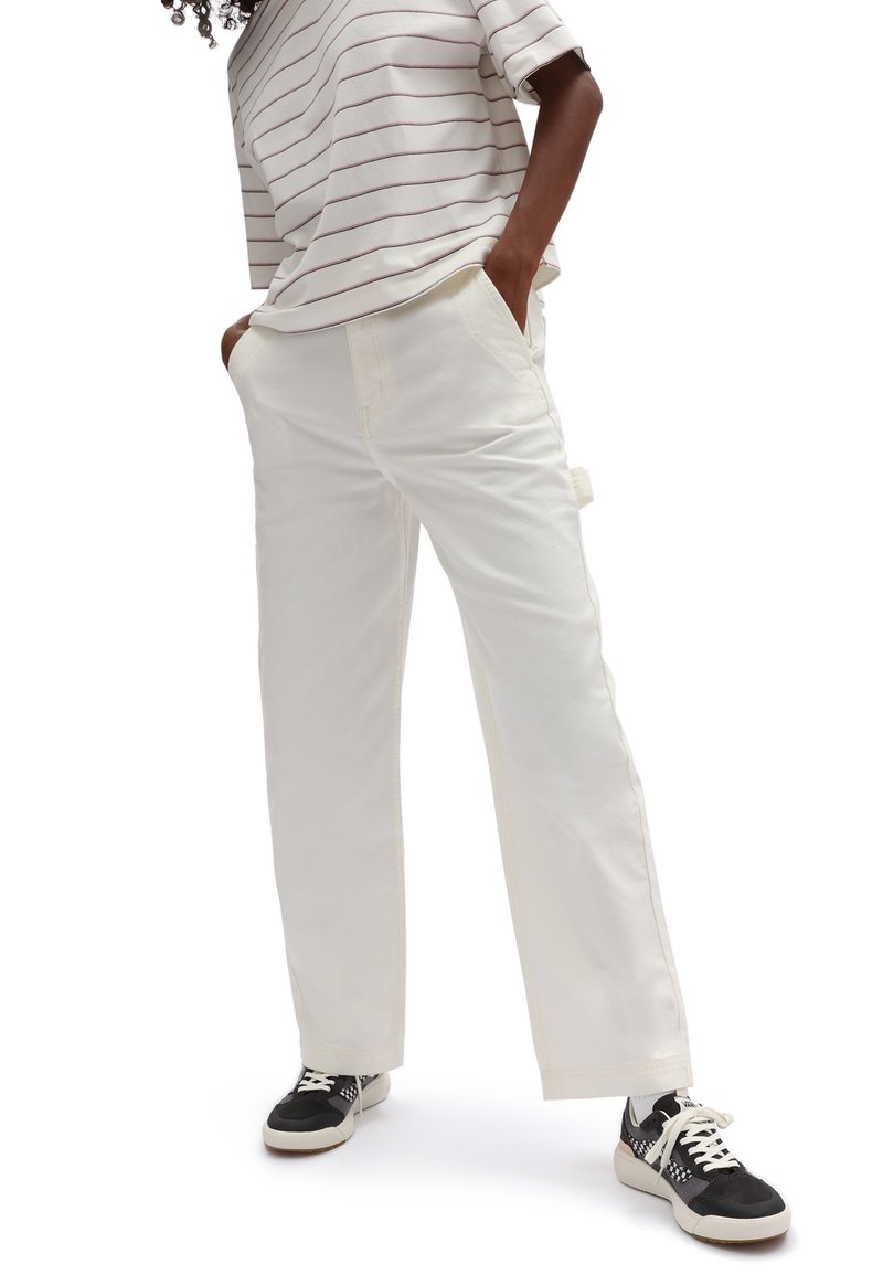 White, straight-leg pants made from cotton with side pockets. Paired with a striped top and black sneakers with white soles.