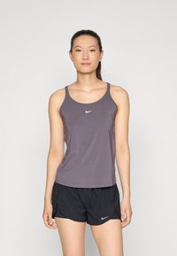 Ærmeløs atletisk tanktop i mørkegrå, lavet af let materiale, med et hvidt Nike-logo på brystet, parret med sorte shorts.