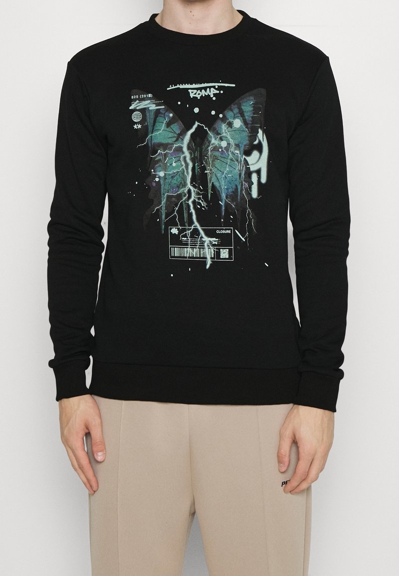 Felpa nera con collo rotondo e maniche lunghe. Presenta un design grafico con ali di farfalla e fulmini in tonalità di verde acqua e bianco.