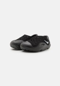 Black casual shoes with a smooth rubber sole, perforated upper for breathability, and a sleek design featuring a contrasting white logo.