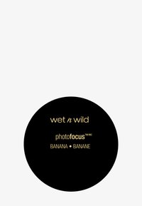 Emballage noir circulaire avec un texte doré. Étiquettes "wet n wild" et "photofocus" ainsi que "BANANE" en anglais et en français. Surface lisse.