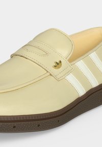 Μπεζ δερμάτινο loafer με λευκές τρεις ρίγες, χρυσό λογότυπο Adidas και υφασμένη καφέ λαστιχένια σόλα.