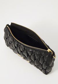Svart skinn clutch-veske med quiltet design, gullglidelås og innvendig lomme, med en teksturert, polstret overflate.