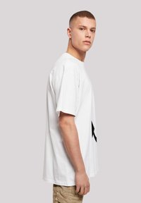 White cotton t-shirt with short sleeves, relaxed fit, featuring a black graphic design on the front. Simple, smooth texture, crew neck.