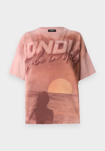 T-shirt oversize rose avec un graphique de coucher de soleil, le texte "DONDI" et un design en silhouette. Fabriqué en coton doux.