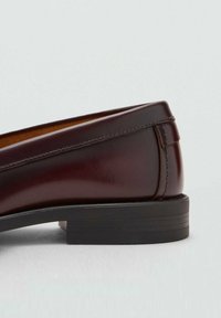 Loaferi din piele burgundă cu un design elegant, bot rotund și un toc jos din cauciuc negru; au detalii de cusătură și un finisaj neted.