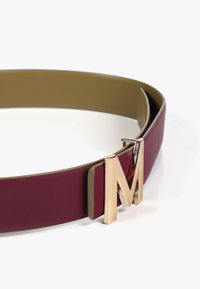 Burgundin nahkavyö, jossa on kultasävyinen M-solki. Ominaisuuksiin kuuluu sileä pinta ja kaksikerroksinen muotoilu, jossa on kontrastiväri sisäpuolella.