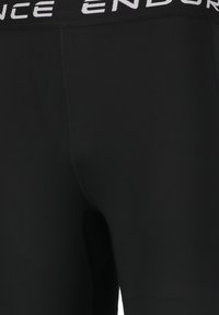 Zwarte leggings van rekbaar materiaal met een brede tailleband met de witte tekst "ENDURANCE". Glad textuur en aansluitend ontwerp.