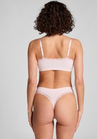 Roze geribbelde bralette met kantafwerking, verstelbare bandjes en bijpassende string met kantaccenten en een soepele tailleband, gezien vanaf de achterkant.