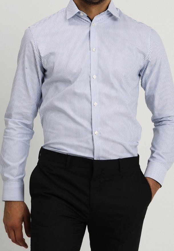 Ljusblå och vit randig skjorta med en figurnära design, långa ärmar, knäppkrage och vita knappar, tillsammans med svarta byxor.