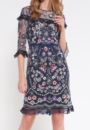 Granatowa sukienka z prześwitującymi rękawami do łokcia, ozdobiona wielokolorowym haftem kwiatów i motyli oraz falbanowanym dołem.