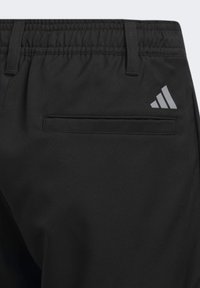 Mustat urheiluhousut, joissa on joustava vyötärönauha, taka-tasku ja harmaa Adidas-logo. Sujuva kangas, jossa on mattapinta.