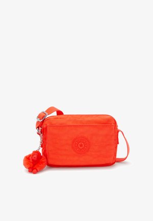 Oranje stoffen schoudertas met een getextureerde afwerking, voorzien van een logo-opdruk aan de voorkant en een afneembare rode aap sleutelhanger.