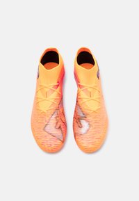 Scarpe da calcio di un vivace arancione con un design testurizzato a gradiente che presenta accenti rosa, tomaia in mesh e un logo nero a contrasto vicino alla caviglia.