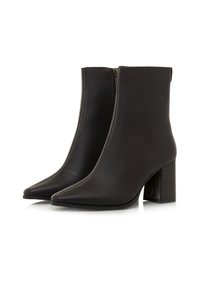 Par de botas de cuero negras hasta el tobillo con punteras puntiagudas, cremalleras laterales y tacones gruesos sobre fondo blanco.
