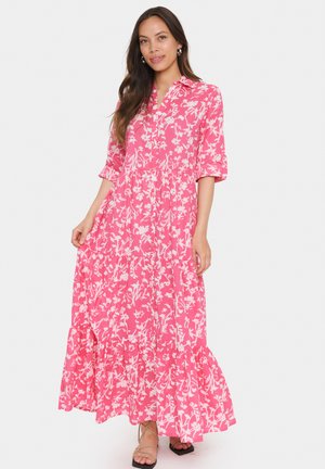 Robes maxi florales roses avec un design à volants, manches longues, col et motifs botaniques blancs. Tissu léger et coupe décontractée.