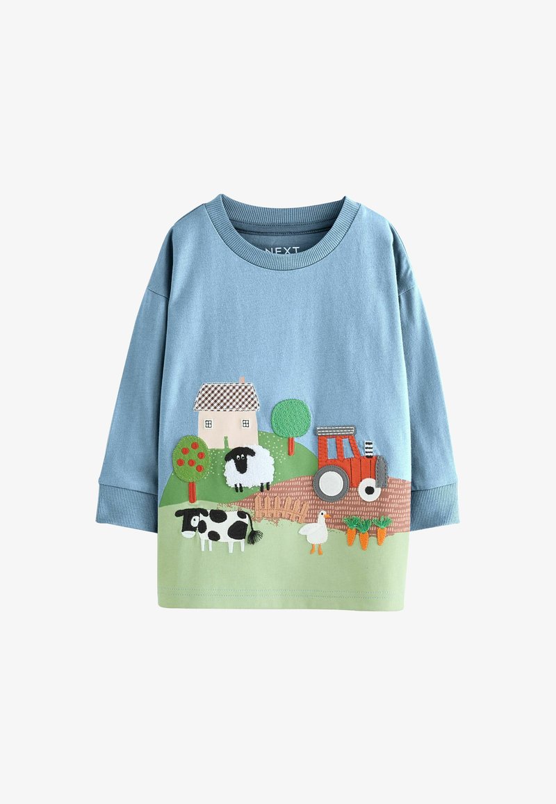 Chemise bleue à manches longues pour enfants avec des appliques sur le thème de la ferme comprenant une maison, des arbres, des moutons, une vache, une oie, un tracteur et des carottes.