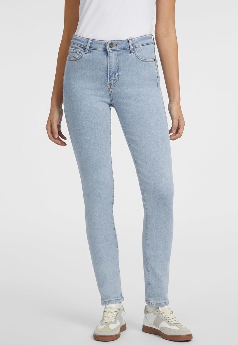 Ljusblå skinny jeans i denim med hög midja, framfickor och knäppning. Matchas med vita sneakers med beige detaljer.