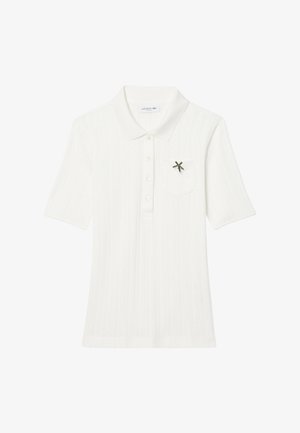 White polo shirt with short sleeves, textured fabric, five buttons, and a front pocket featuring a small green Lacoste logo detail.
