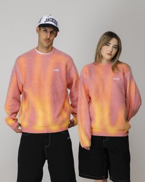 Maglioni oversize e morbidi in sfumature di rosa e arancione, con polsini e orlo a costine, abbinati a pantaloni corti neri. Logo mostrato sul petto.