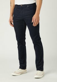 Dark navy slim-fit jeans made of denim with a smooth texture, featuring a classic five-pocket design and a small front button.